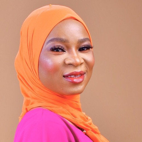 A portrait of a Muslim lady dressed in orange hijab and purple shit.