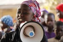 A woman wearing a headscarf passionately holds a megaphone, ready to speak out and advocate for her cause.