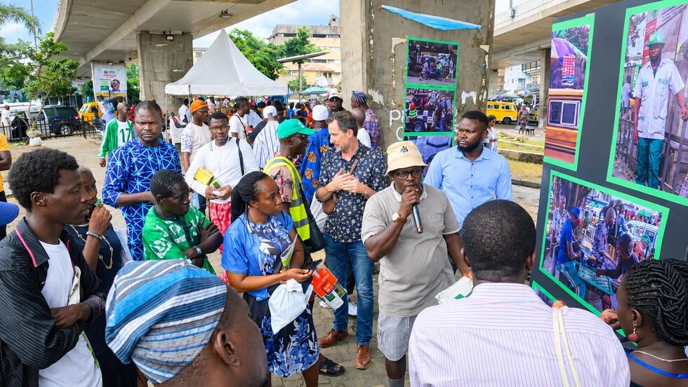 Image of man speaking with a group of people at the As We See Am exhibition.